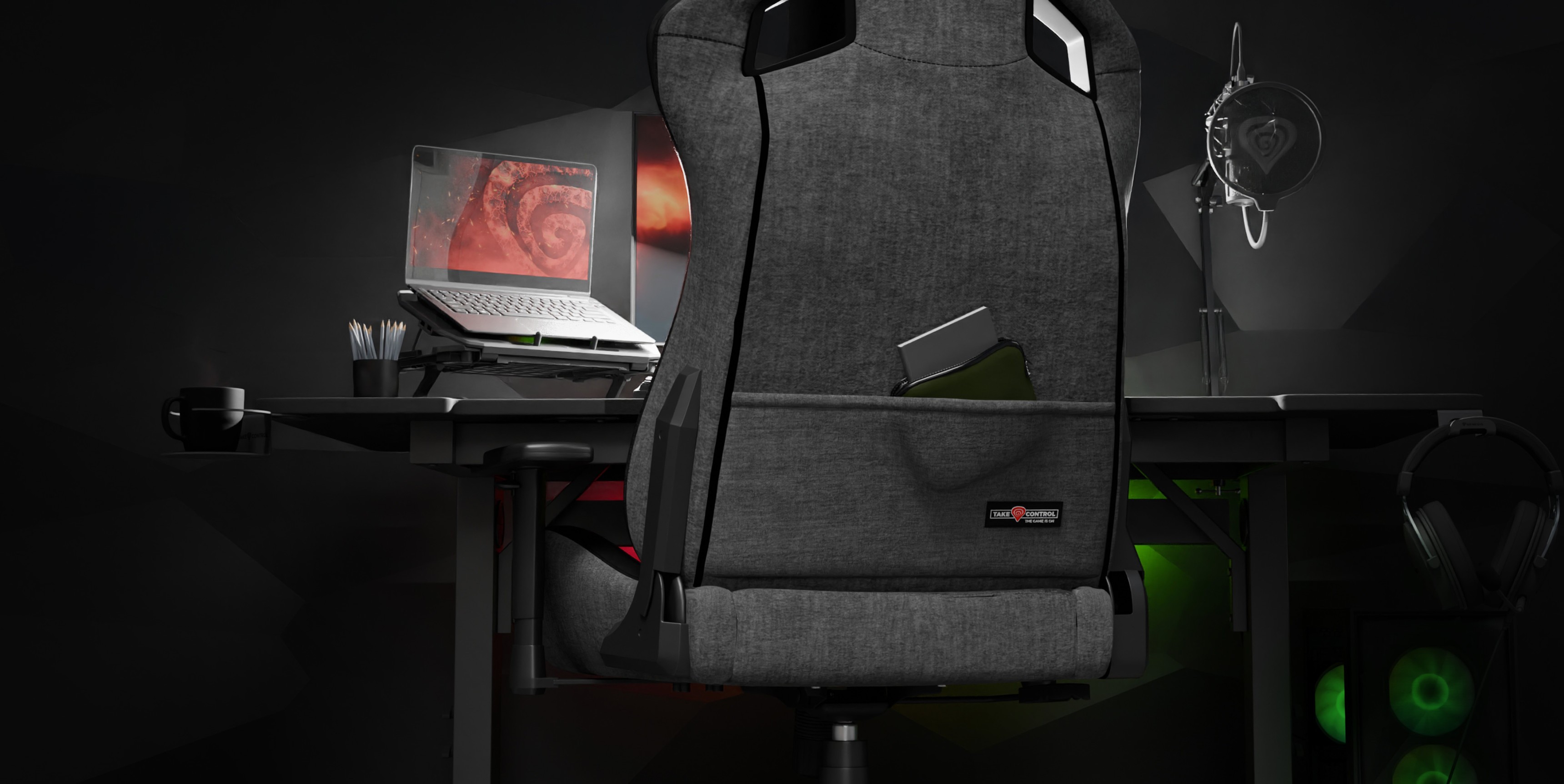 Grauer Genesis Nitro 660 Gaming-Stuhl hinter einem Schreibtisch mit einem Laptop und Gaming-Zubehör in einem schummrigen Raum