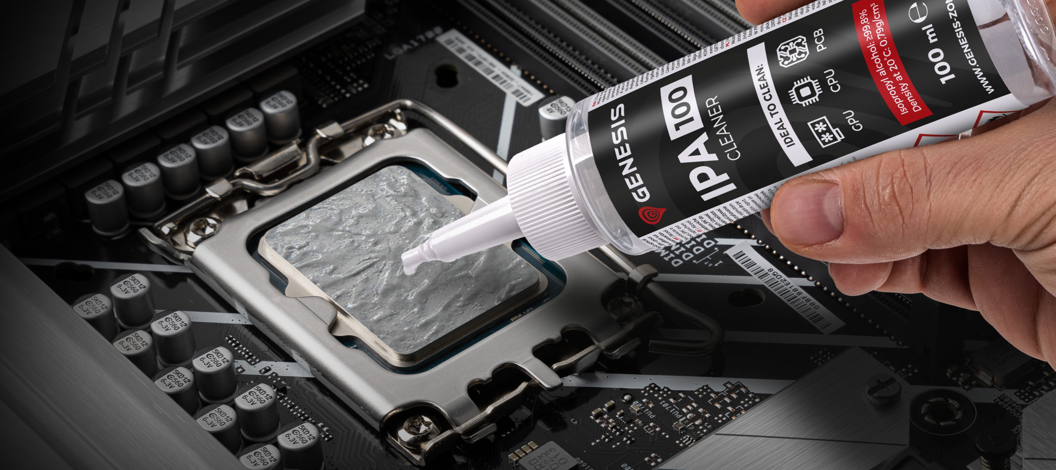 Eine Hand hält eine Flasche Genesis IPA 100-Reiniger und trägt ihn auf einen Computer-CPU-Sockel auf einem Motherboard auf.
