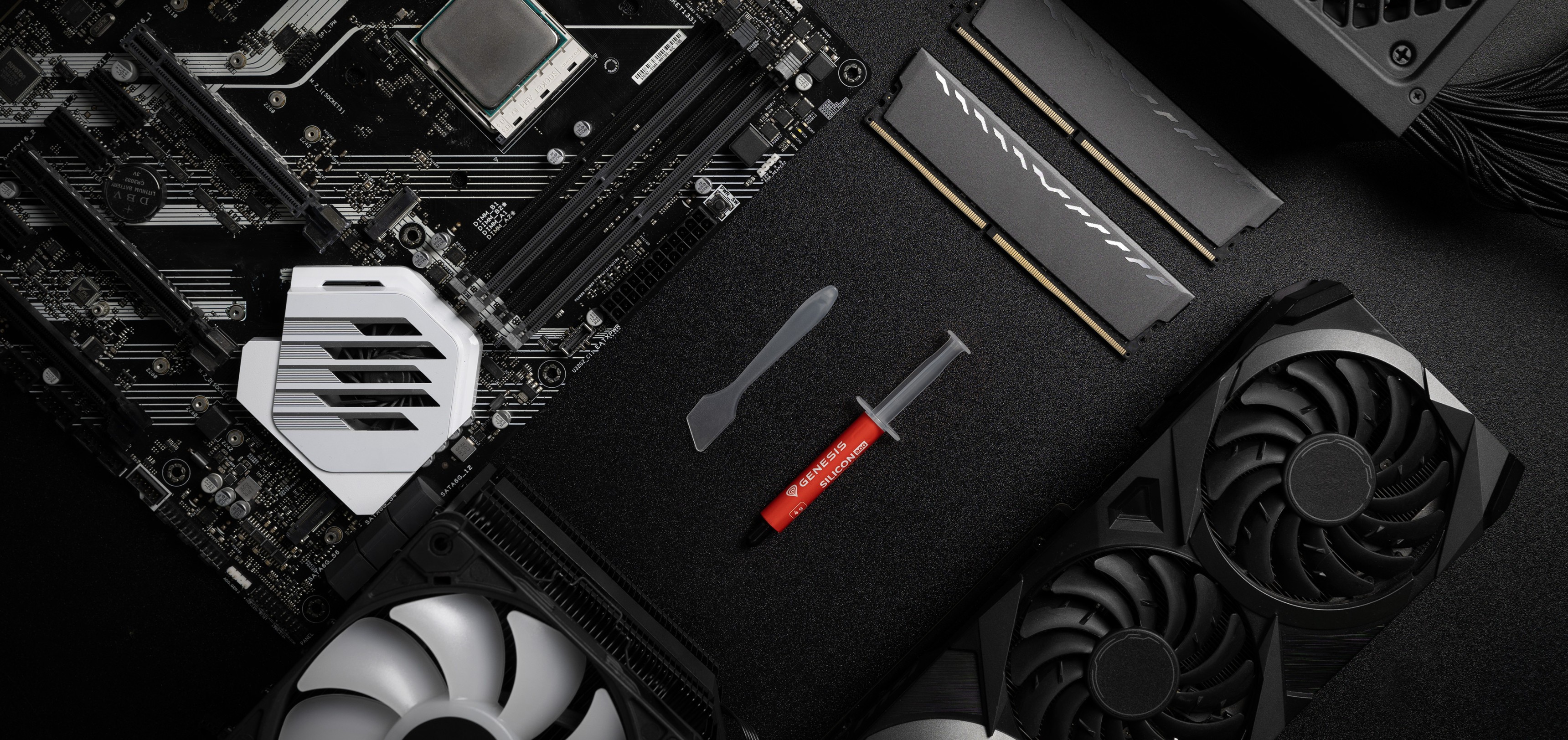 Wärmeleitpastentube mit einem Spatel, platziert auf einem schwarzen Hintergrund neben Motherboard, RAM und GPU