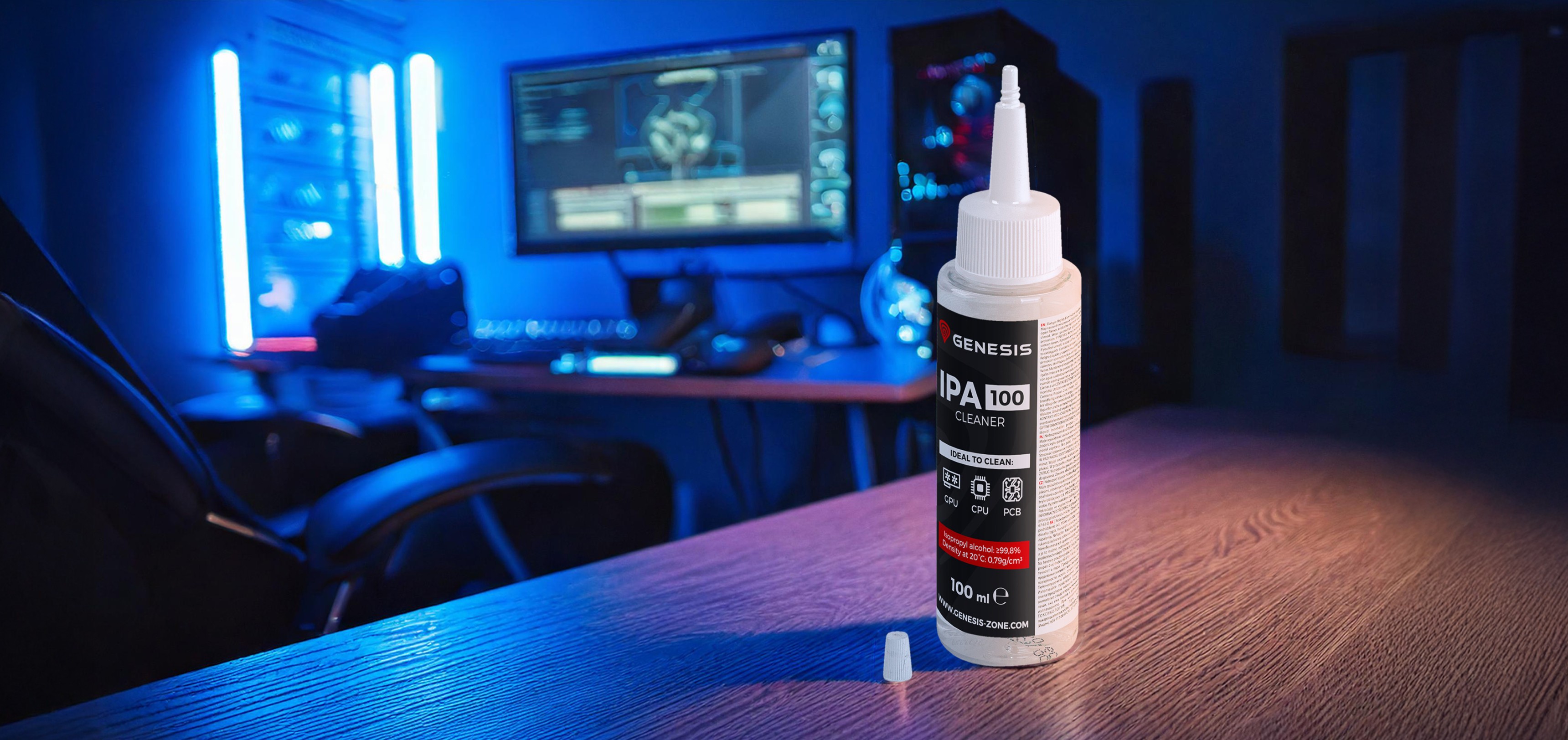 Eine Flasche Genesis IPA 100 Reiniger (100ml) auf einem Holztisch, mit einer Spielkonsole und blauer Beleuchtung im Hintergrund