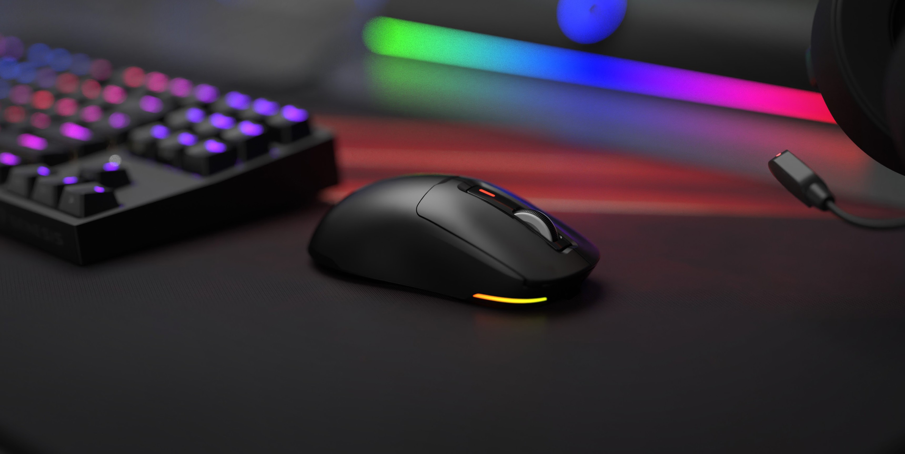 Schwarze Genesis Zircon 660 kabellose Gaming-Maus mit RGB-Beleuchtung, platziert auf einem schlanken Gaming-Schreibtisch neben einer mechanischen Tastatur