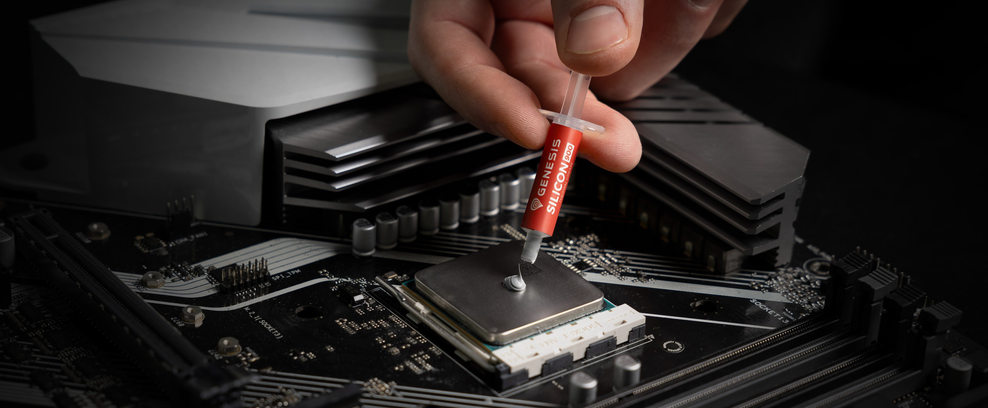 Handauftragen von Wärmeleitpaste aus einer Spritze auf eine CPU in einem Computer-Motherboard-Setup