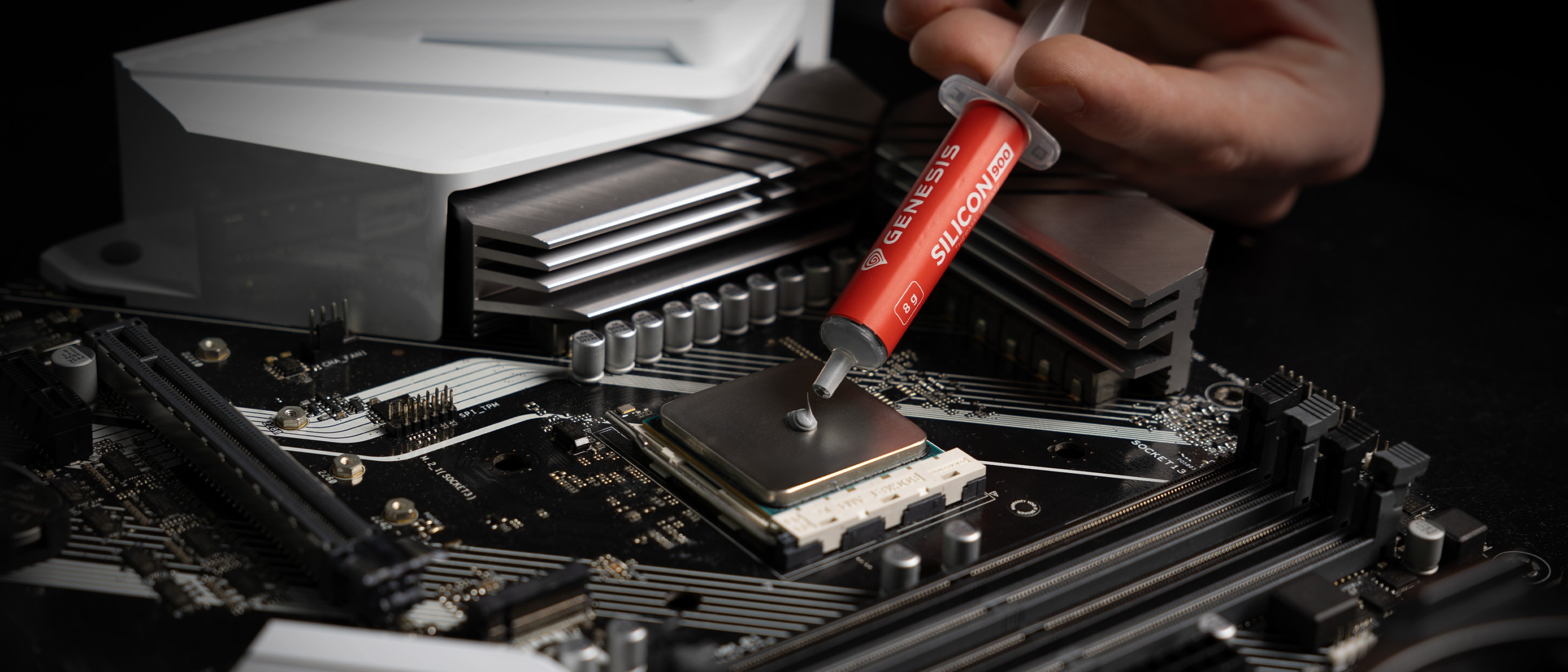 Spritze mit Genesis Silicon Wärmeleitpaste beim Auftragen auf eine CPU auf einem Motherboard
