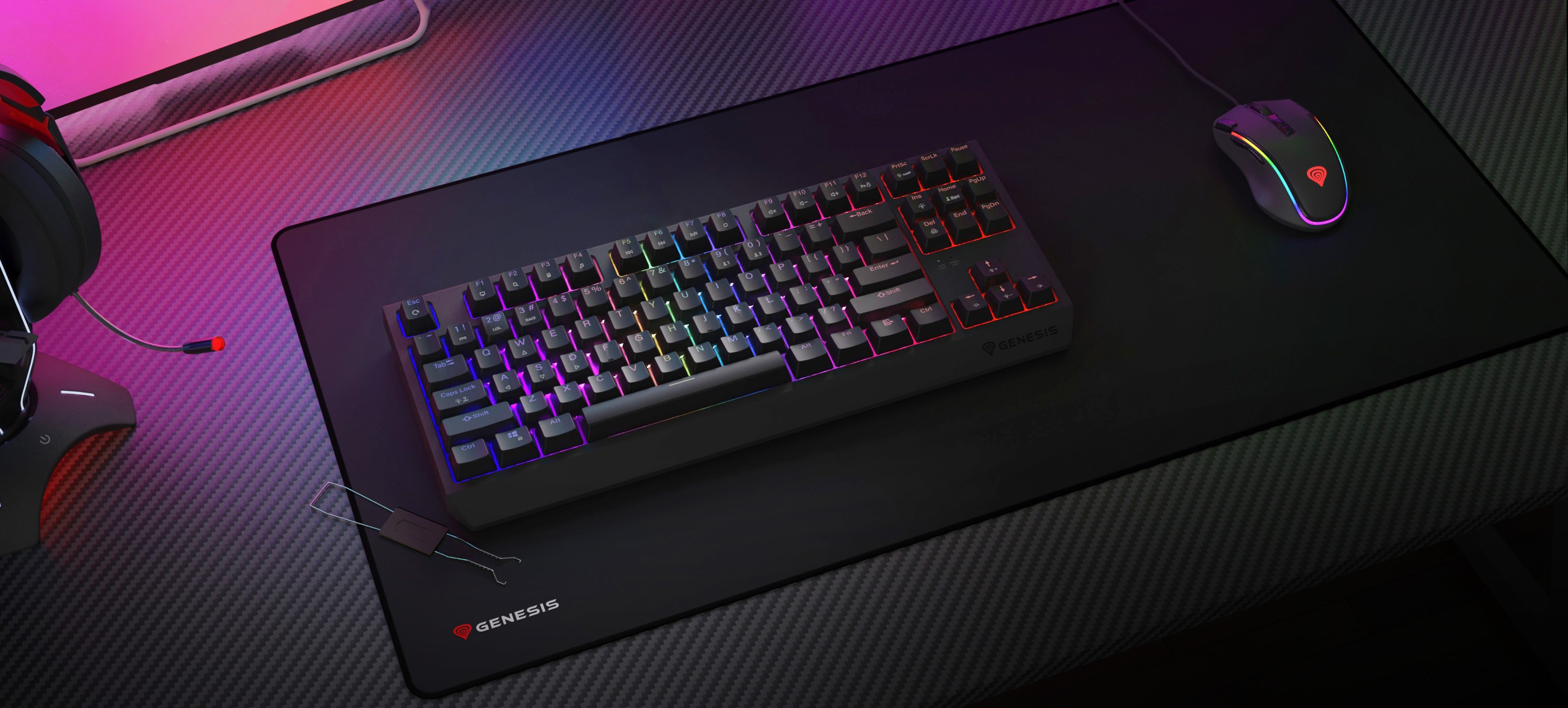 Kabellose mechanische Gaming-Tastatur mit RGB-Beleuchtung, die auf einem großen Mauspad neben einer Gaming-Maus und einem Headset steht