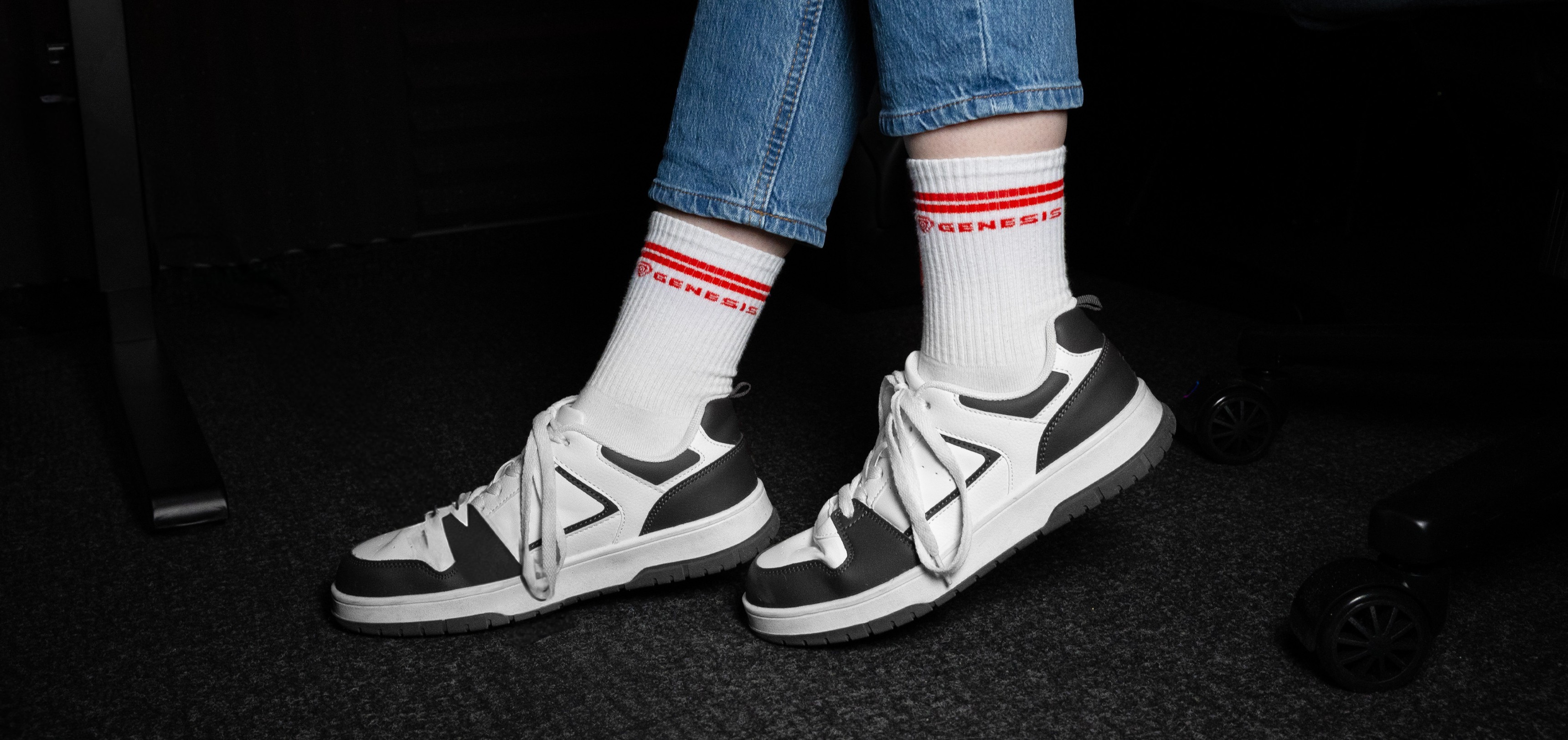 Sportsocken in Weiß mit roten Streifen, gepaart mit grauen und weißen Sneakers und blauen Jeans