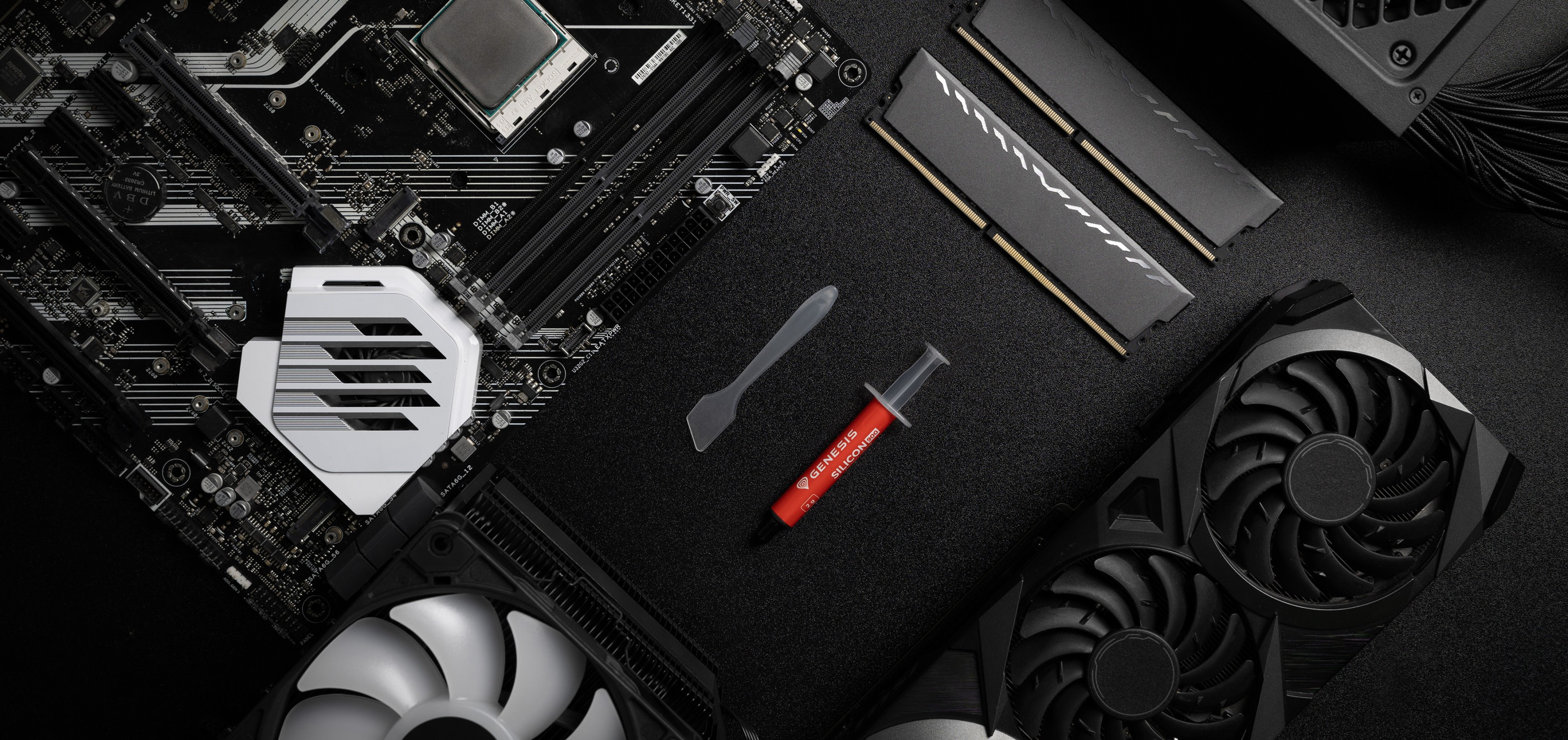 Wärmeleitpastentube mit einem Spatel auf einem Motherboard, neben RAM- und GPU-Komponenten